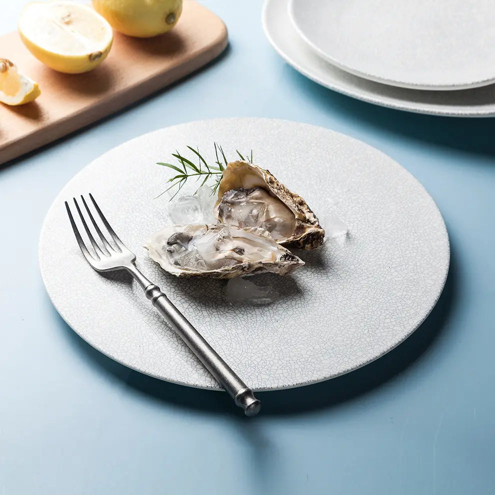 Plato de cerámica blanco con textura y un acabado craquelado sutil de la colección Lucerne Sophie, diseñado para una mesa elegante.