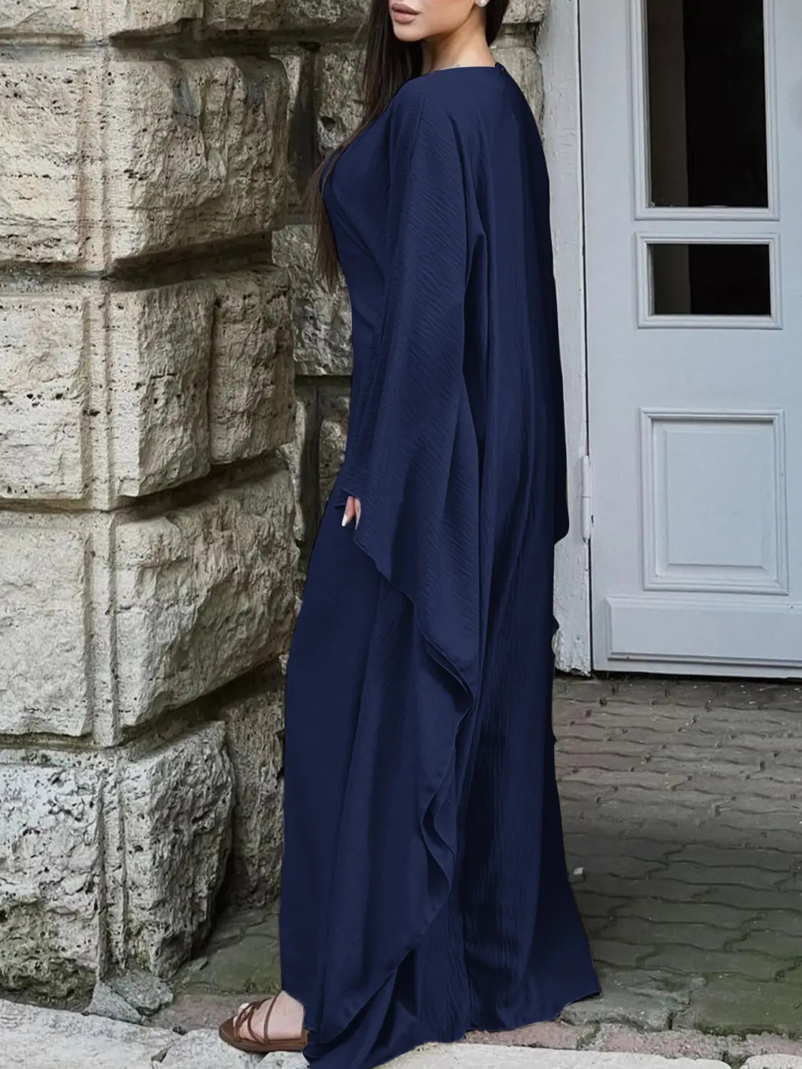 A flowing navy blue satin maxi dress with wide draped sleeves loose fit and ruffled hem.