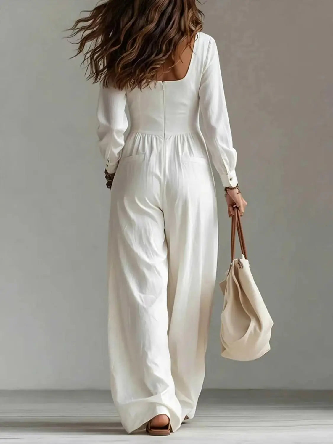 Une combinaison blanche fluide à manches longues pour femmes, avec encolure carrée et pantalon à jambes larges.