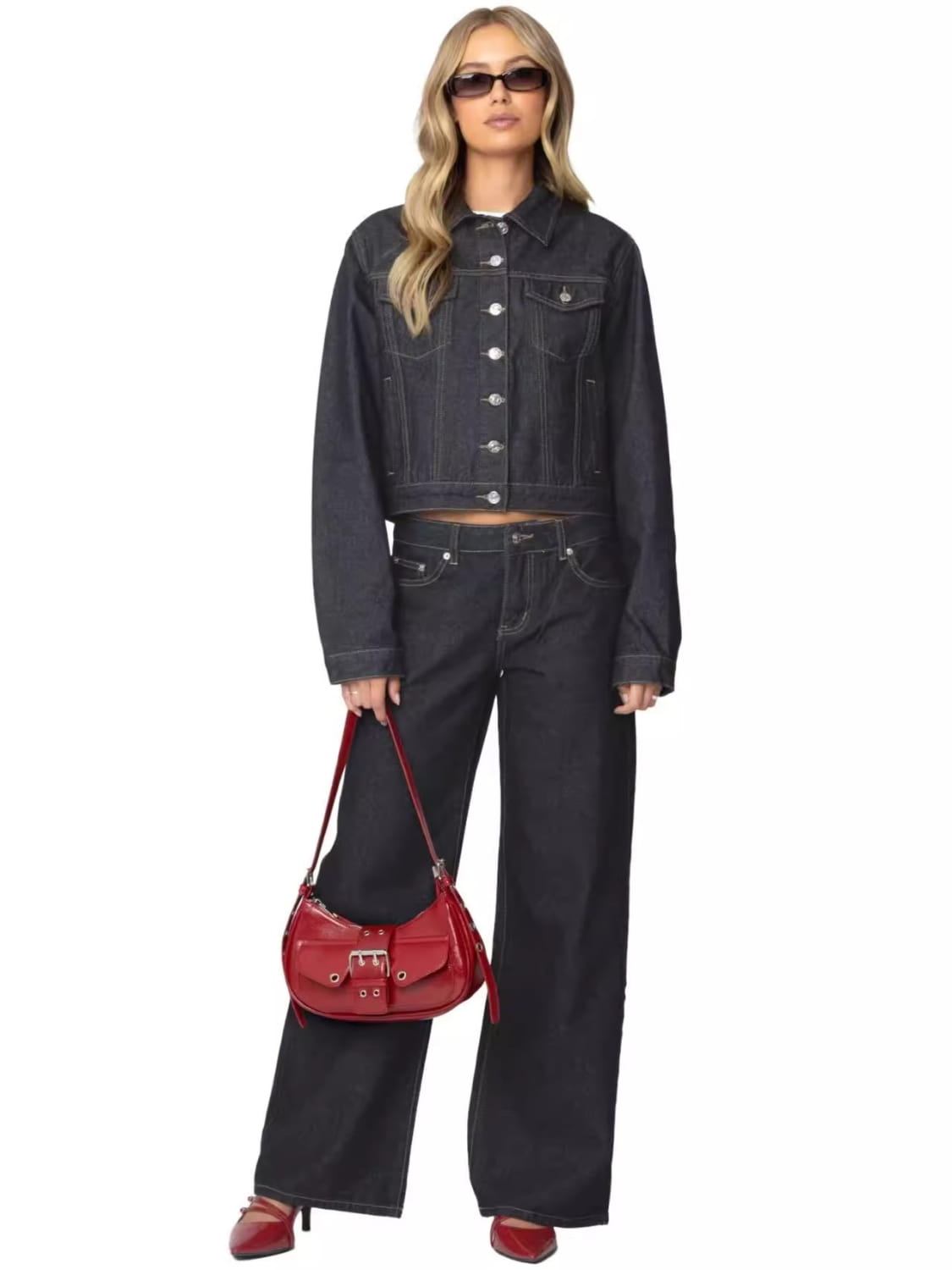A vibrant red glossy leather crossbody bag with structured design and silver toned hardware featured alongside high waist wide leg denim jeans.