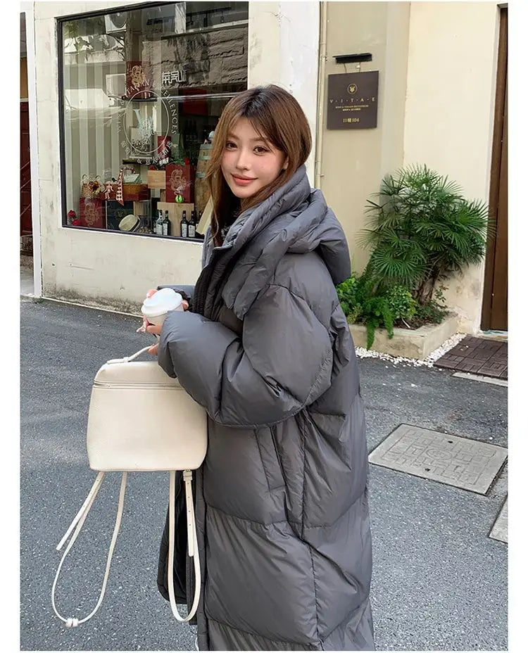Women’s long quilted winter puffer coat in gray with a hood and insulated design for cold weather protection.