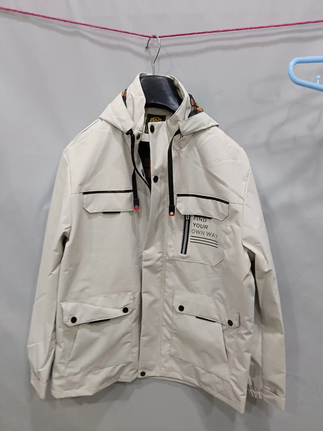 Beige men winter hooded parka coat with black trim button closures and a front pocket featuring the text find your own way.
