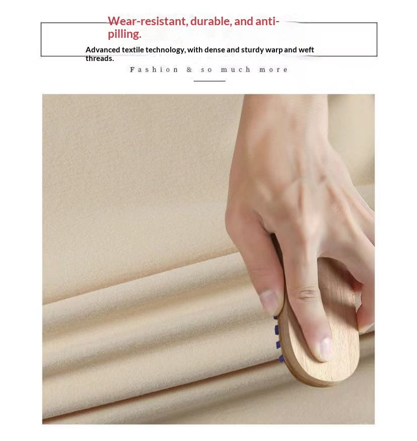 A hand gently holds a wooden fabric brush with purple bristles smoothing a durable beige textile of the Dralon turtleneck thermal base layer top.