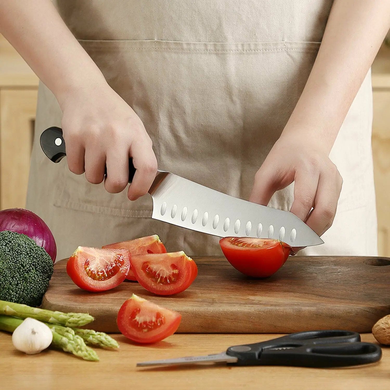 Couteau de chef élégant en acier inoxydable, doté d’un manche noir, avec des encoches ovales distinctives le long de la lame, inclus dans un ensemble de couteaux de chef comprenant des ciseaux de cuisine en acier inoxydable.