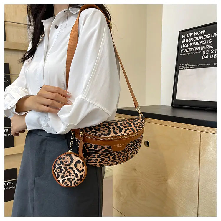 Sac banane à imprimé léopard avec pochette à monnaie et bordure en cuir brun, agrémenté de lanières en cuir assorties et d’un charme circulaire.