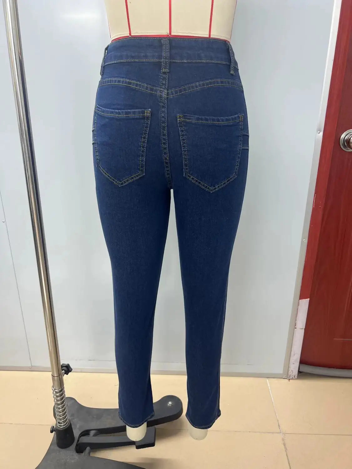 Le côté arrière des leggings en jean bleu nuit à taille haute présente une coupe ajustée, avec des coutures visibles sur les poches arrière.