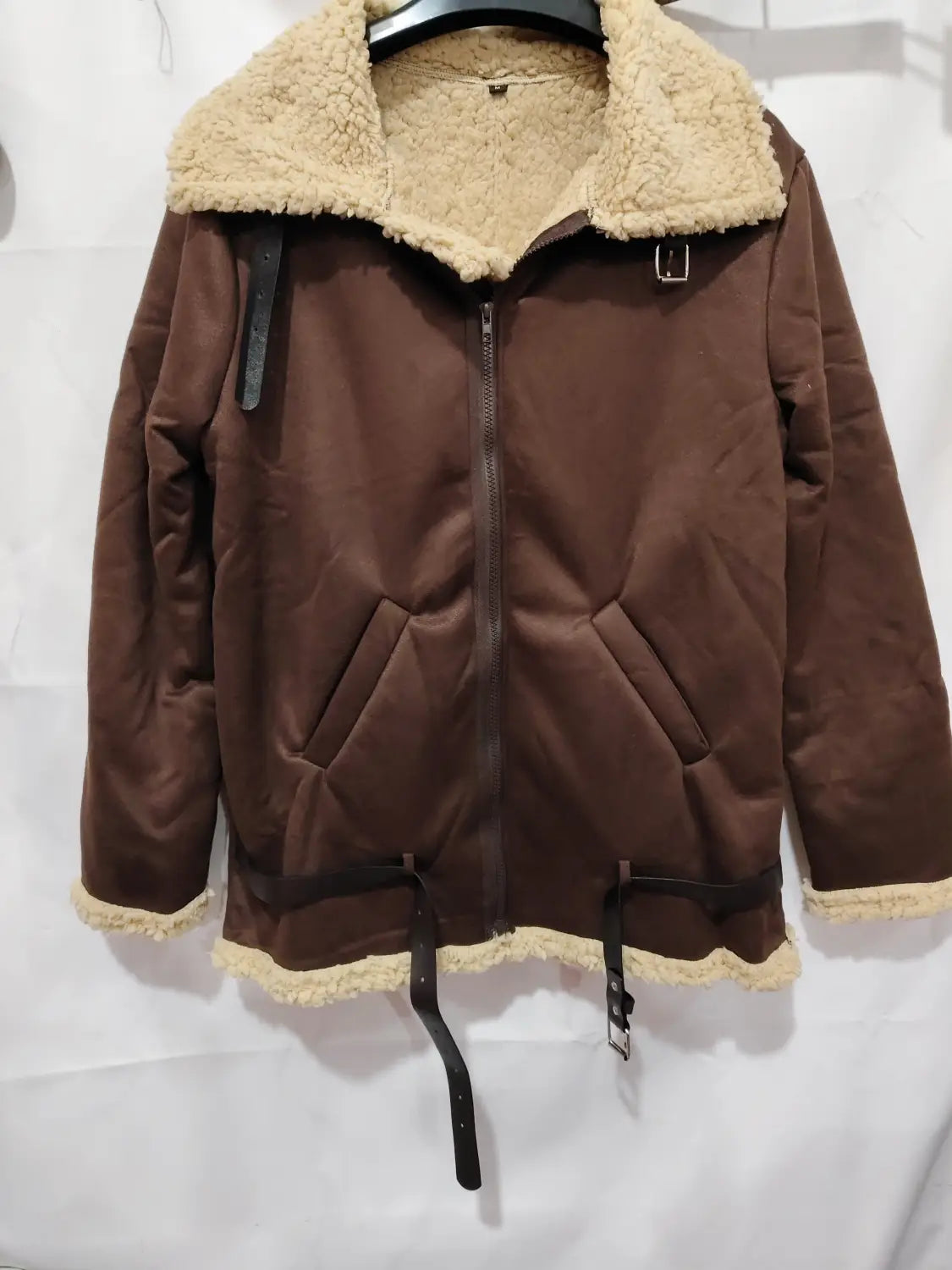 Men shearling bomber jacket in brown with shearling lining and black leather straps and buckle details.