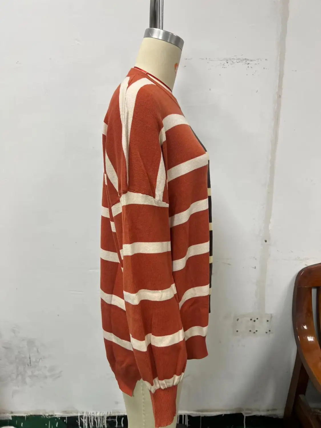 A cozy women’s oversized knit sweater featuring bold orange and cream horizontal stripes with ribbed hem and cuffs.