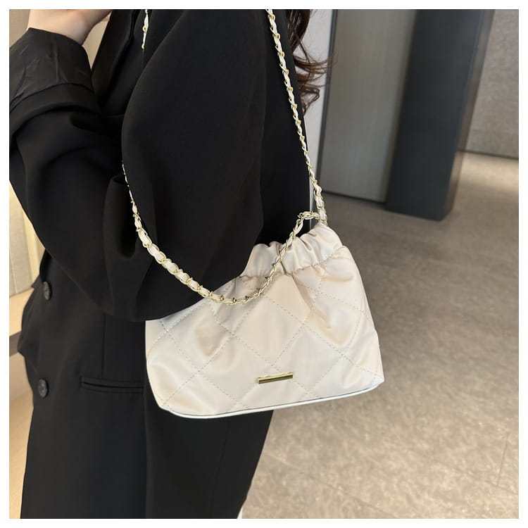 A white quilted faux leather crossbody bag with a gold-tone chain strap is showcased.
