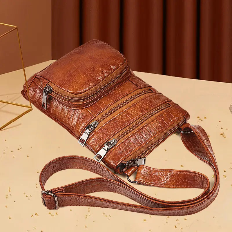 Retro crocodile textured soft brown leather crossbody bag with multiple zippers and silver toned hardware.