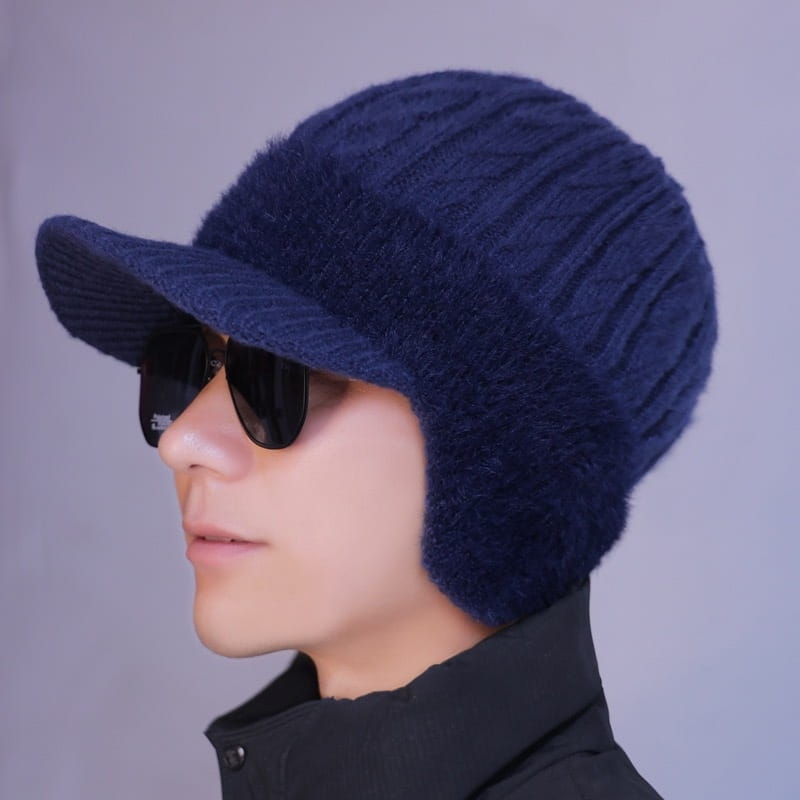 dunkelblaue gestrickte fleecegefütterte Mütze mit Krempe und Kunstfell-Ohrklappen für die Winterzeit.