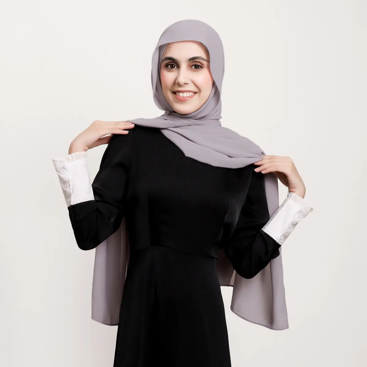 Un hijab magnétique en mousseline gris clair doux, réalisé dans un tissu léger, drapé avec élégance sur les épaules.