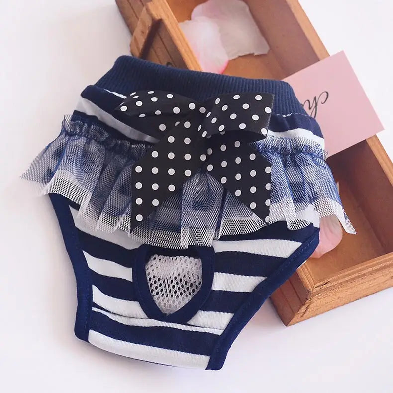 Navy blue and white striped washable dog physiological pants pet diaper with black polka dot bow and sheer ruffled trim designed as sanitary shorts.