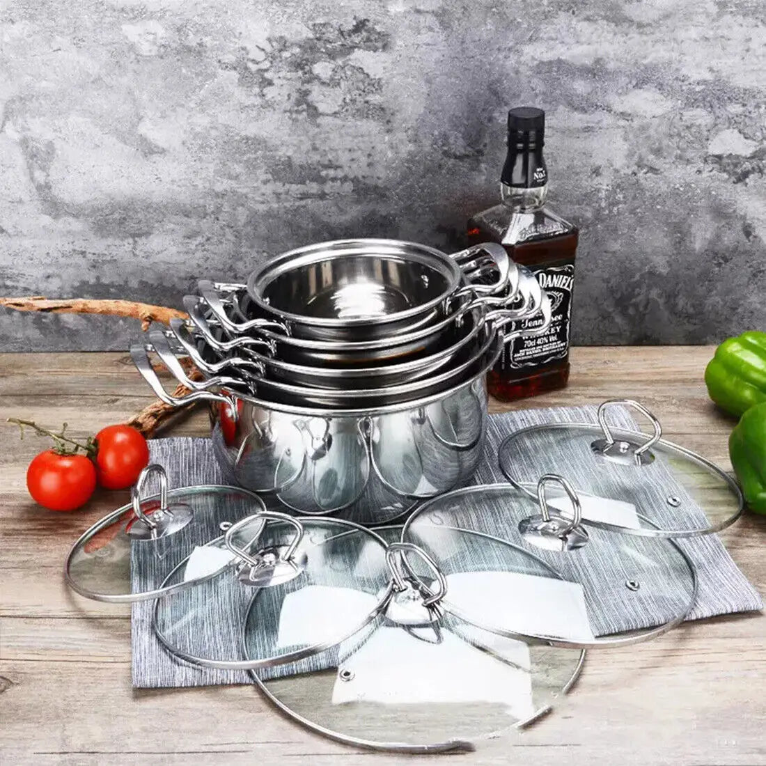 Stack of stainless steel induction cookware pots with matching glass lids in a polished silver finish.