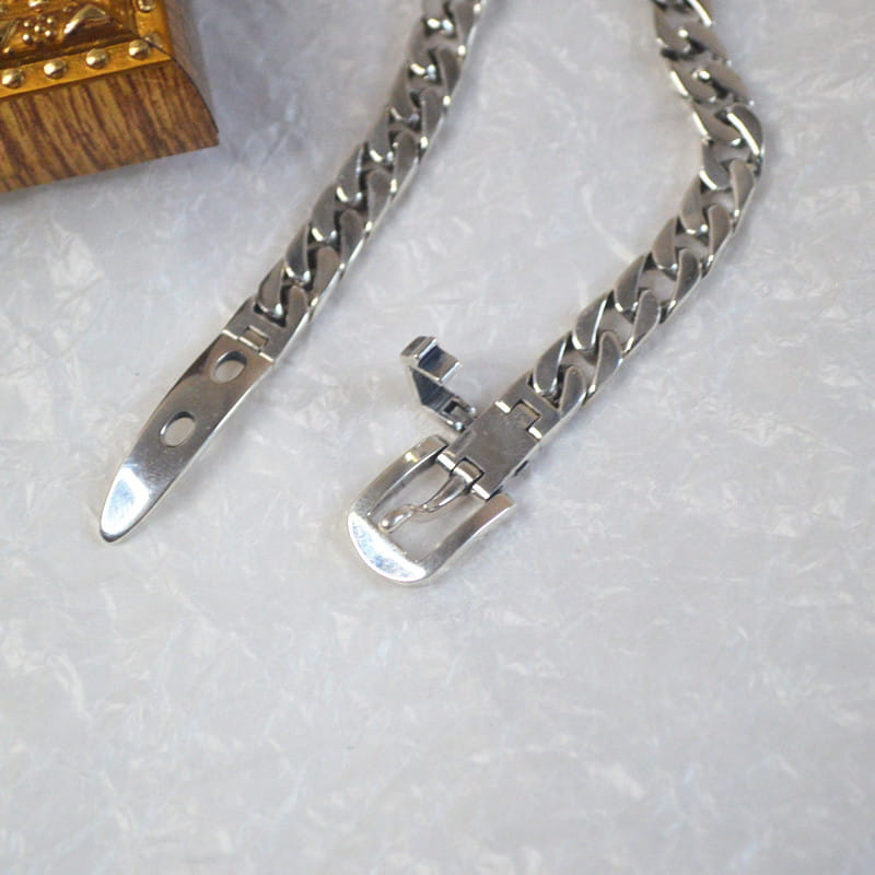 Women’s platinum plated stainless steel buckle chain bracelet in silver tone with polished finish and curb link design.