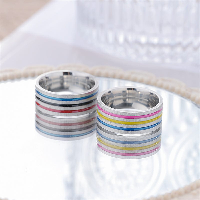 Two stacked stainless steel unisex band rings with colorful rainbow enamel stripes on a silver-toned metal base.