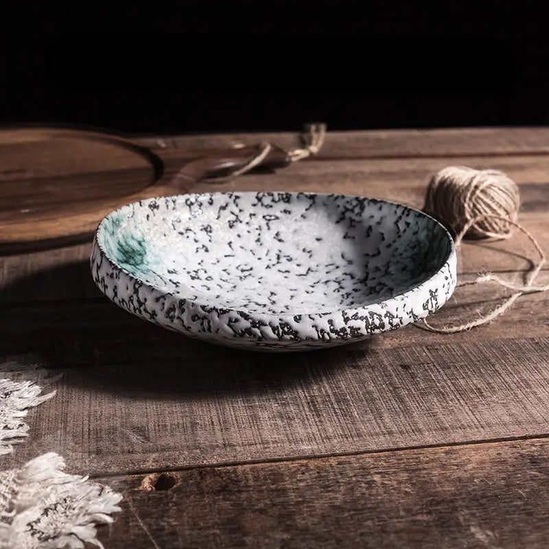 A white ceramic speckled serving bowl with black and teal glaze and a rustic handcrafted texture designed for home kitchens.