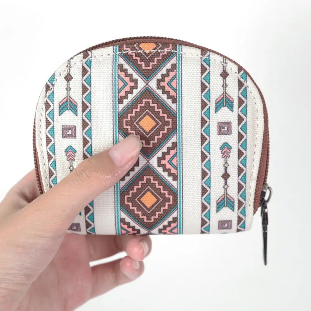 A compact white fabric woven geometric card wallet and portable coin purse with a tribal pattern in brown teal and orange and contrasting brown zipper trim.