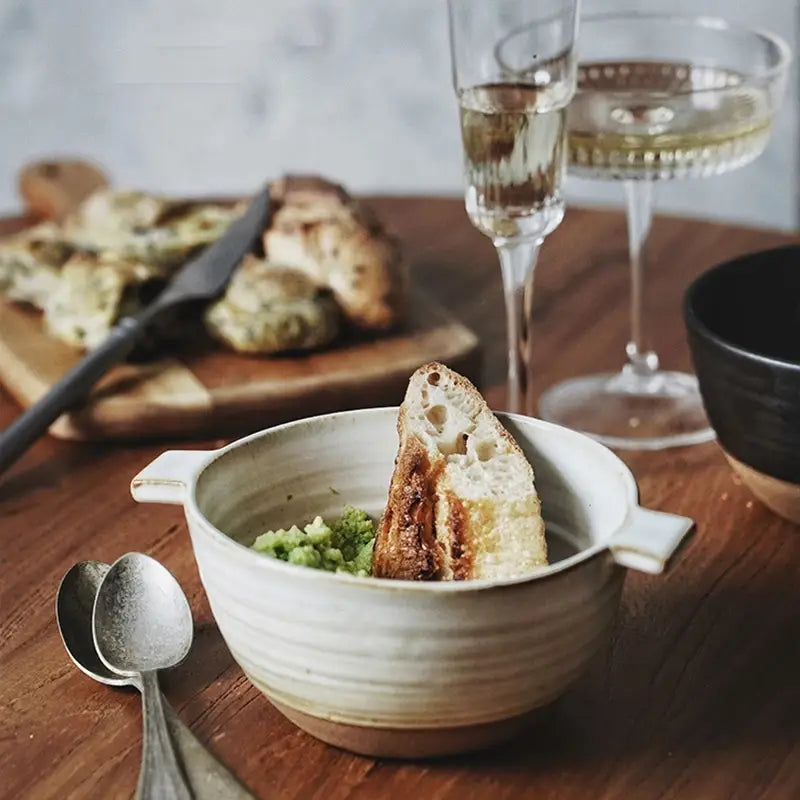 A rustic white Japanese stoneware 6 inch binaural ceramic soup bowl filled with green puree and accompanied by a slice of toasted bread.