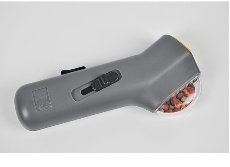 Gray handheld pet hair remover with a transparent collection chamber filled with colorful fur pellets designed for use with a dog training snack launcher pet treat shooter.