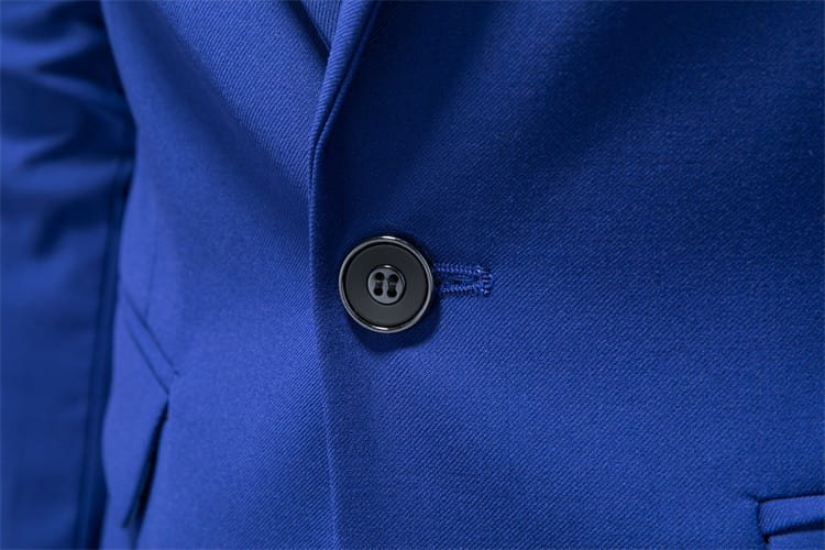 Elegante botón metálico negro en una chaqueta de vestir empresarial de pana con ajuste slim, sobre un tejido azul real intenso.