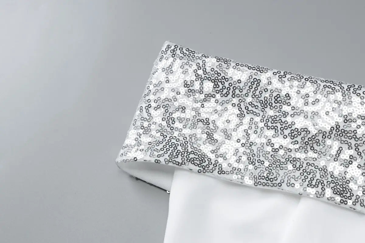 a shimmering silver sequined fabric cuff with a subtle gradient of metallic sheen on a sequined off-the-shoulder white bodycon mini dress