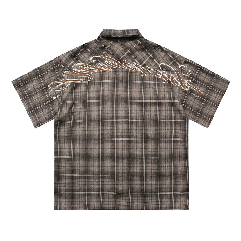The back side of a dark brown and gray plaid embroidered short sleeve button-up shirt featuring a cursive logo across the back.