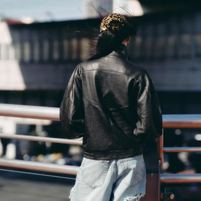 Veste bomber en cuir de litchi noir pour femmes, présentant une surface texturée et des détails de couture classiques