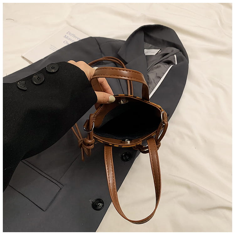 Brown leather bucket bag with woven texture and adjustable shoulder strap in retro leopard print suede mini bucket crossbody bag design.