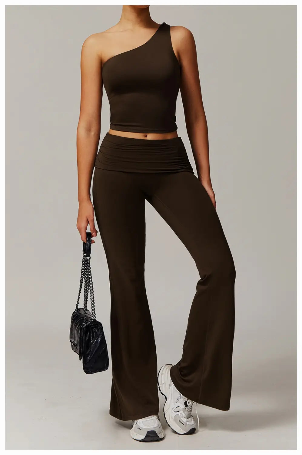 top corto marrón elegante de un solo hombro con silueta entallada y cinturilla fruncida, combinado con pantalones de yoga acampanados de cintura alta.