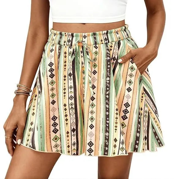 Eine Frau trägt Shorts mit floralen Mustern und hoher Taille im A-Linien-Schnitt mit vertikalen Streifen in erdigen Tönen und geometrischen Mustern, mit einem elastischen Bund.
