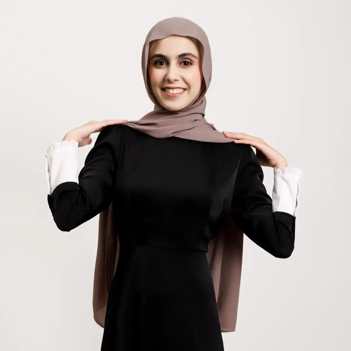 Un hijab magnétique en mousseline taupe doux, au tissu fluide qui se drape avec élégance sur la tête et les épaules, en couleur unie kaki.