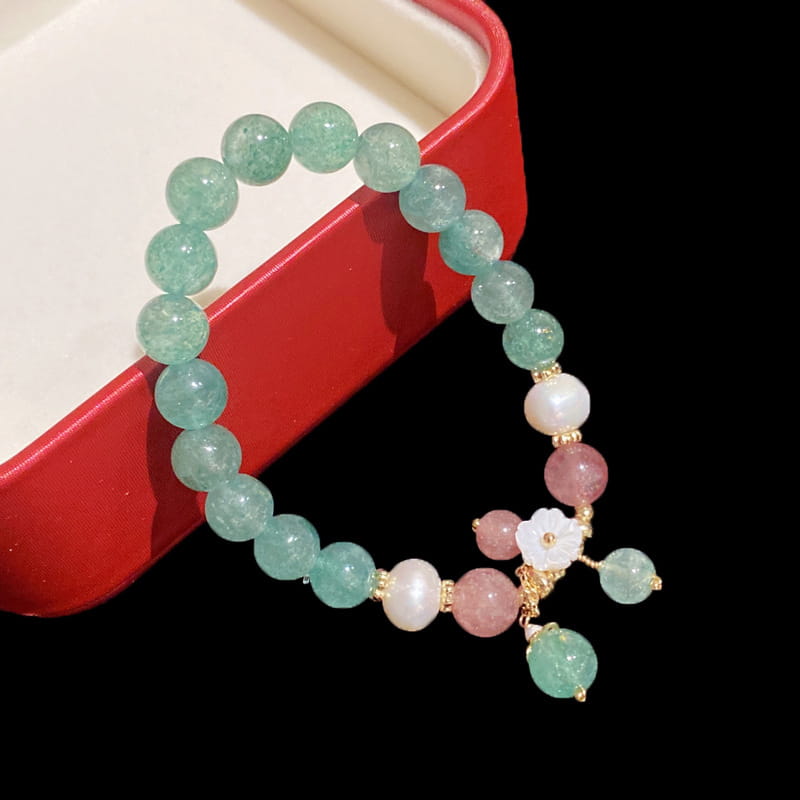 A delicate korean floral green strawberry crystal beaded bracelet featuring translucent green and pink beads with a white floral charm and gold-toned metal accents.