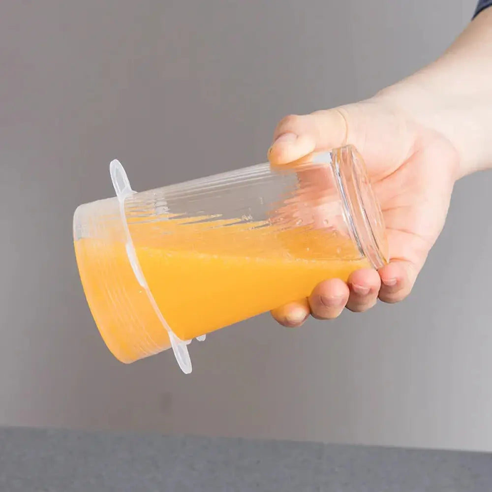Transparent plastic cup with white silicone lid and handle filled with orange juice in 6-pack reusable silicone stretch lids set