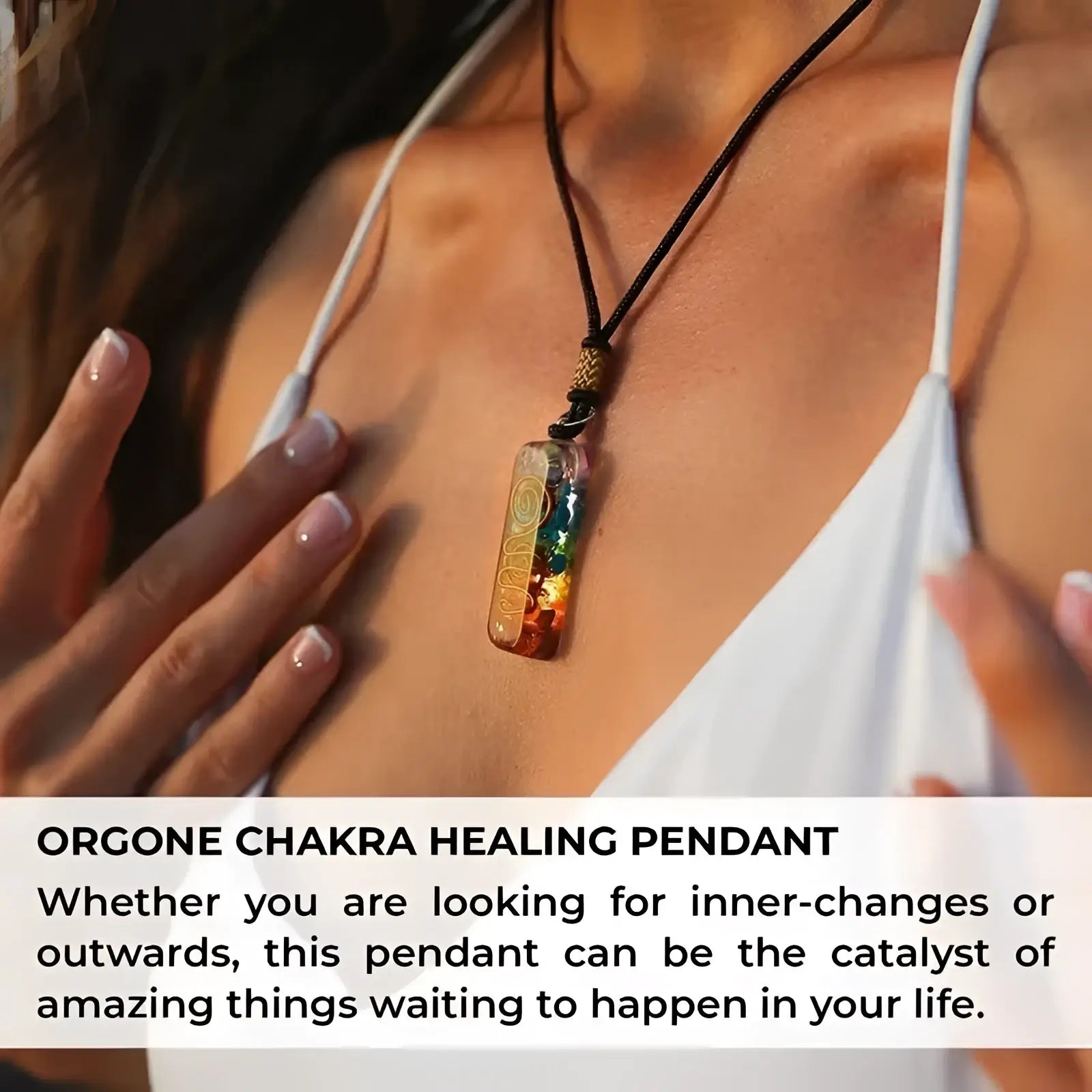 A rectangular translucent amber orgone 7 chakra healing pendant with embedded rainbow stones and gold-toned filigree design