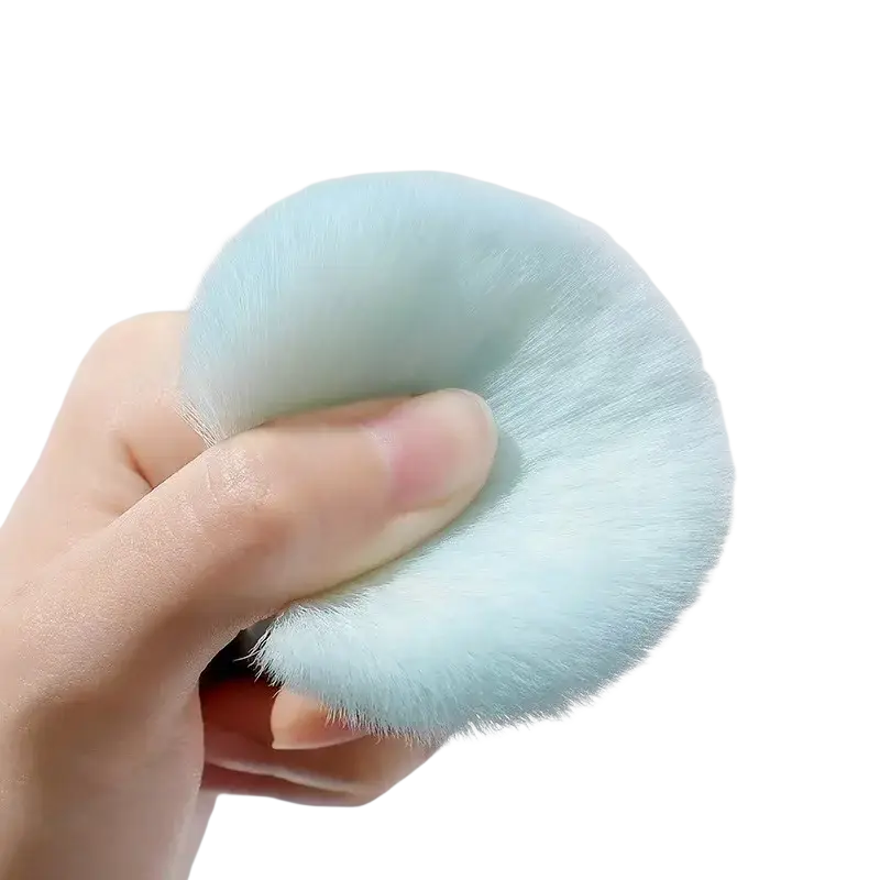 A soft light blue fluffy makeup sponge held in hand from 7 piece pastel makeup brush set with soft bristles