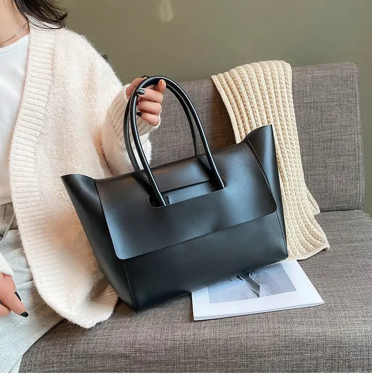 Black leather vintage structured tote bag with top handles designed for everyday use.