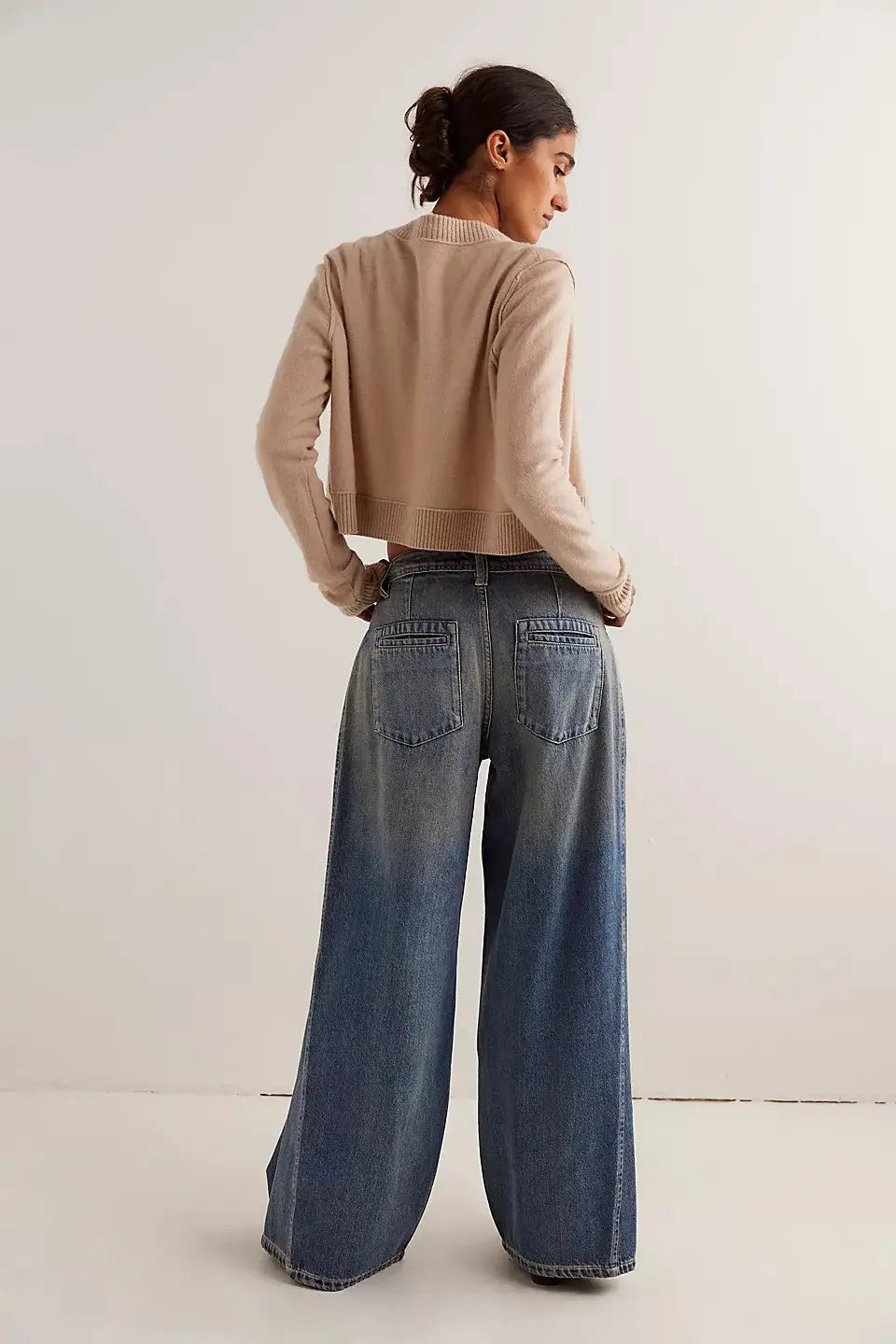Vaqueros retro de mezclilla de pierna ancha en denim azul de lavado medio con costuras clásicas y bolsillos traseros mostrados desde la parte posterior.
