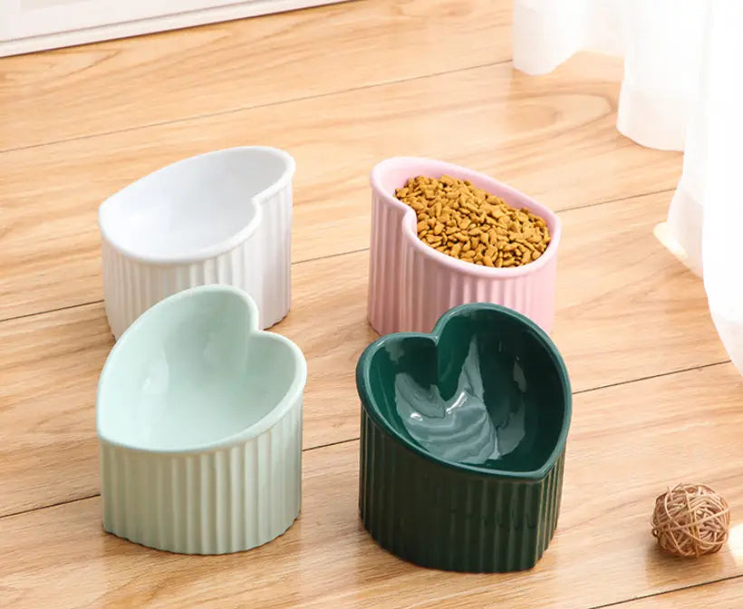 Set of four heart-shaped ceramic pet bowls in pastel and dark green hues with vertical ribbed texture from the tilted ceramic cat bowl set 4 pack.
