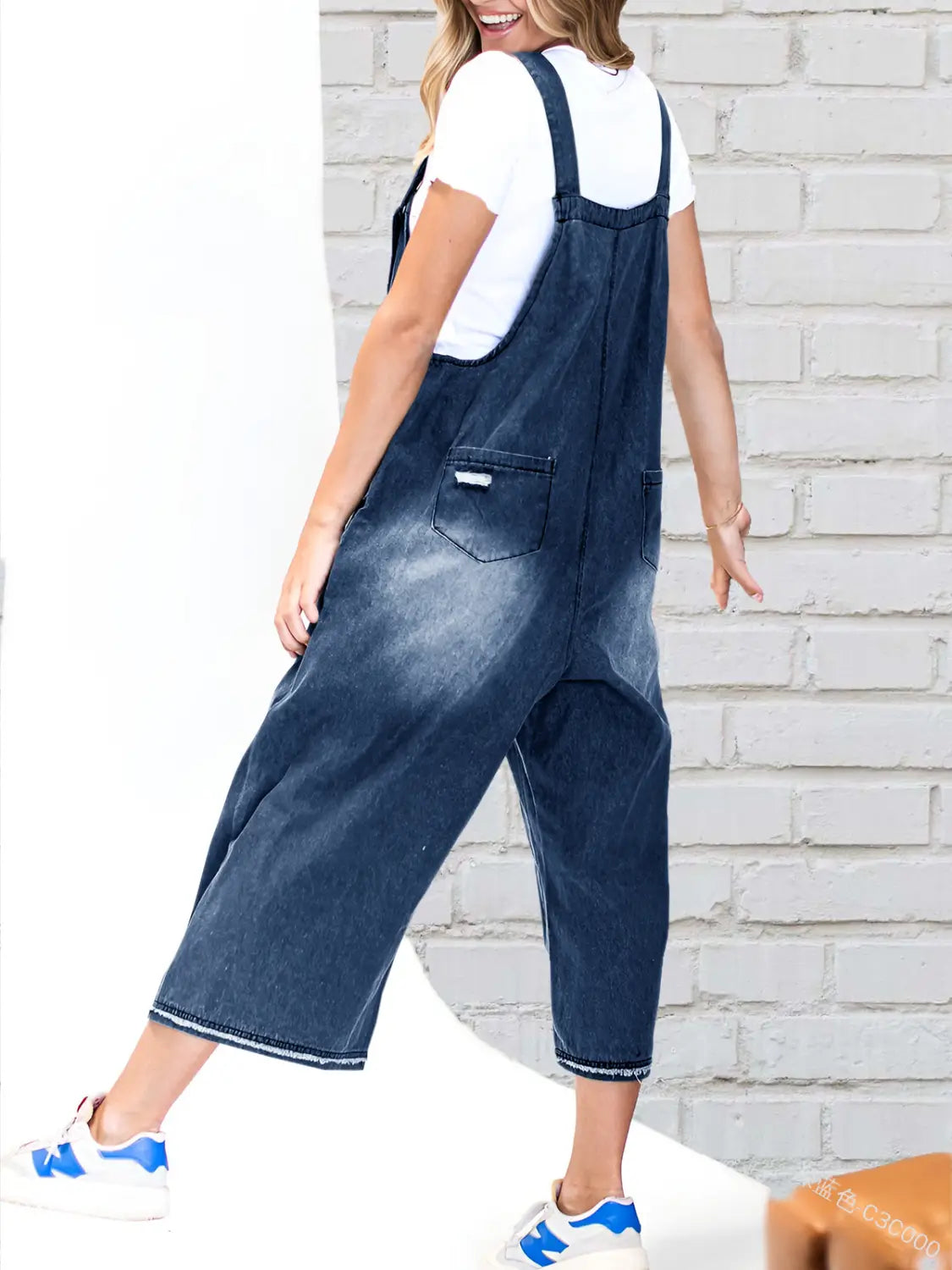 Dark blue distressed denim overalls for women with wide legs, adjustable straps, and a relaxed fit.