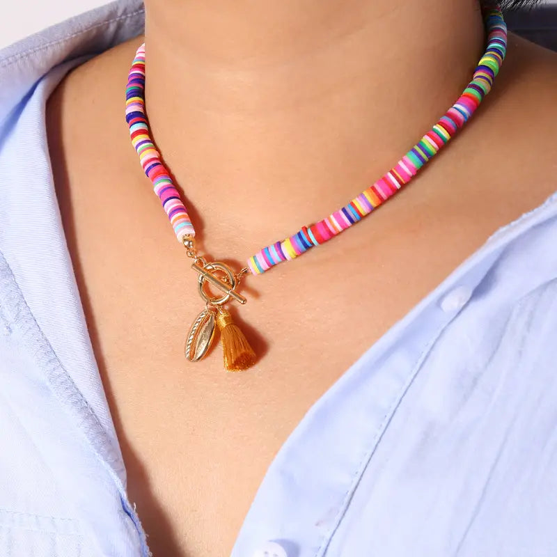A vibrant multicolored beaded bohemian choker necklace with shell and tassel charms featuring a gold-toned toggle clasp.