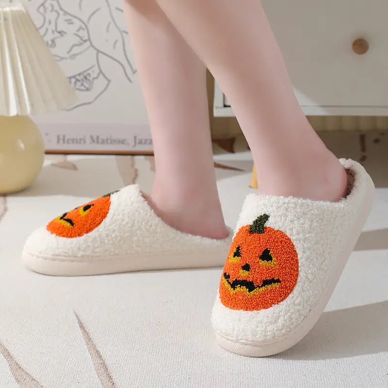white plush jack-o-lantern embroidered halloween slippers featuring orange pumpkin faces with black and yellow details