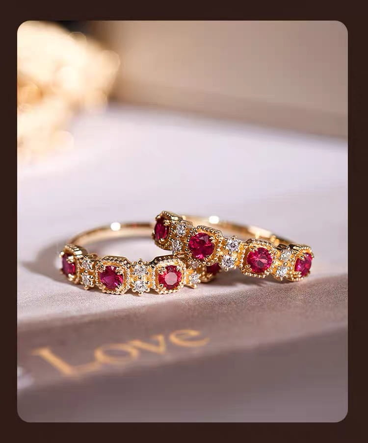 Elegant 18k gold plated band rings featuring prominent round pigeon blood red rubies and smaller sparkling diamonds in a classic intricate design.
