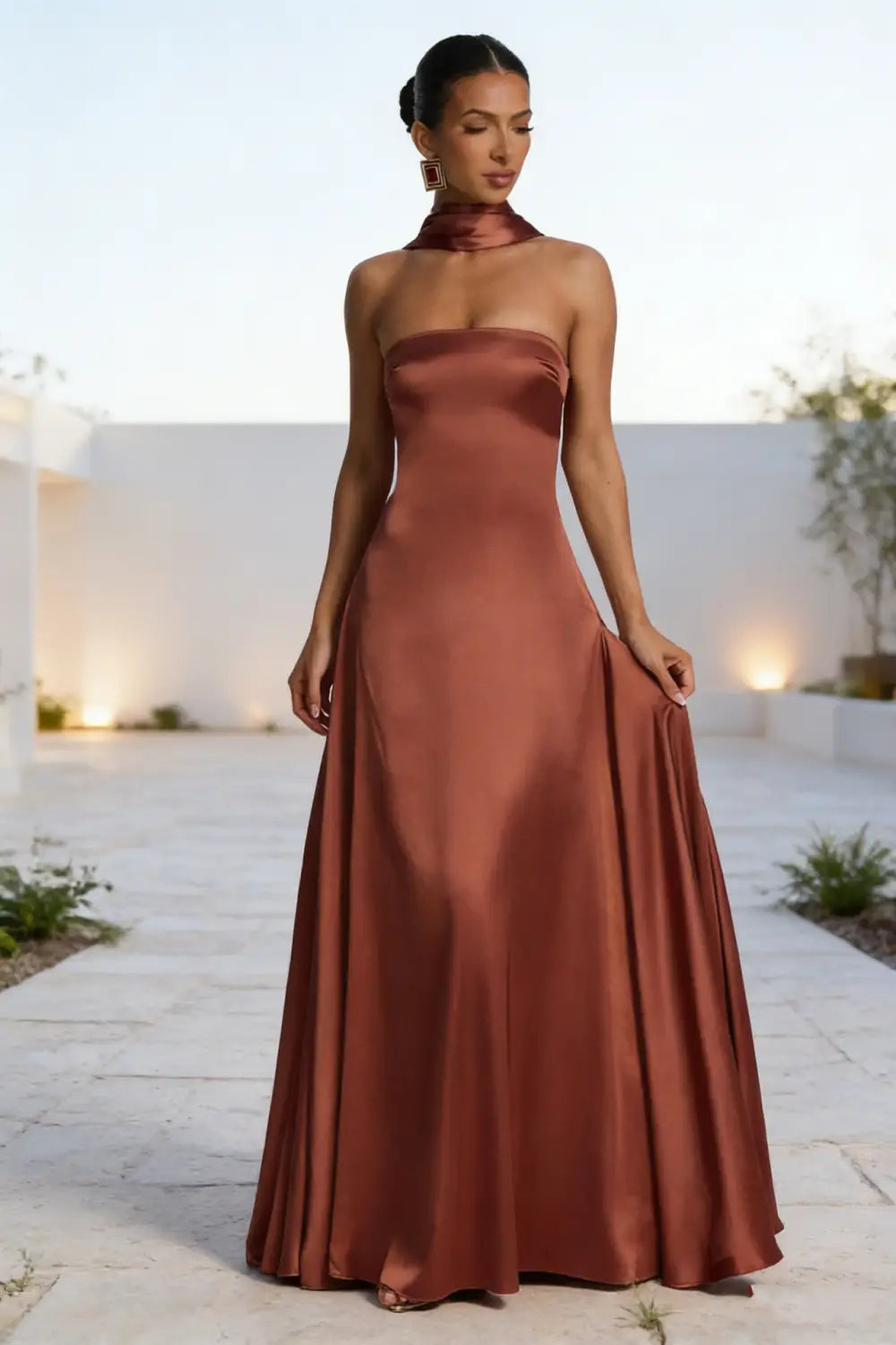 Un elegante vestido de noche de satén color óxido sin tirantes, con escote alto y una silueta entallada.