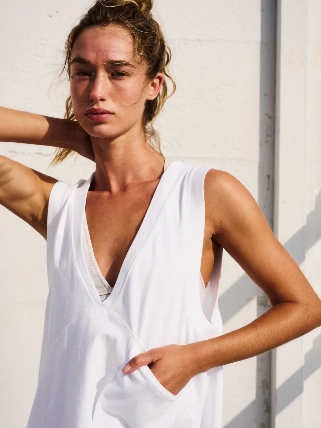White sleeveless cotton wrap vest top with a relaxed fit deep v neck and side pockets.