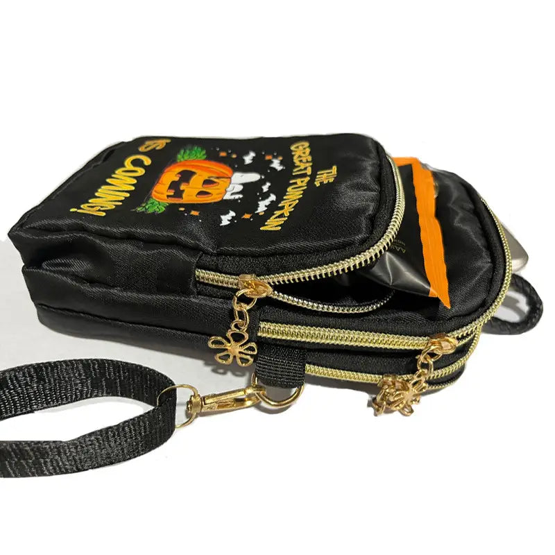 Black Halloween-themed crossbody phone bag with gold zippers, embroidered Snoopy and pumpkin design, and black woven strap.