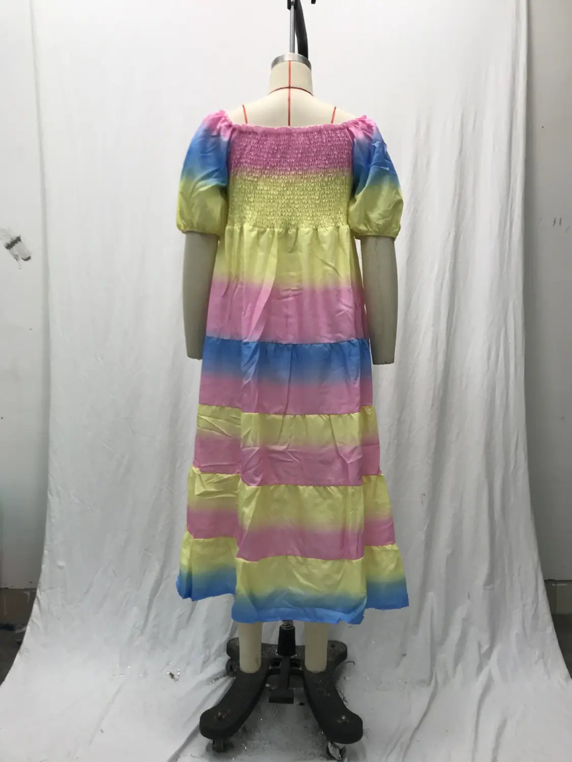 A vibrant rainbow-striped floral print smocked tiered midi dress with a square neckline, puffy sleeves, and a smocked bodice displayed on a mannequin.