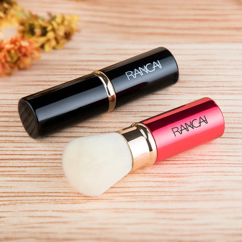 A sleek, compact retractable makeup brush rancai with a glossy red and gold handle and soft white bristles.