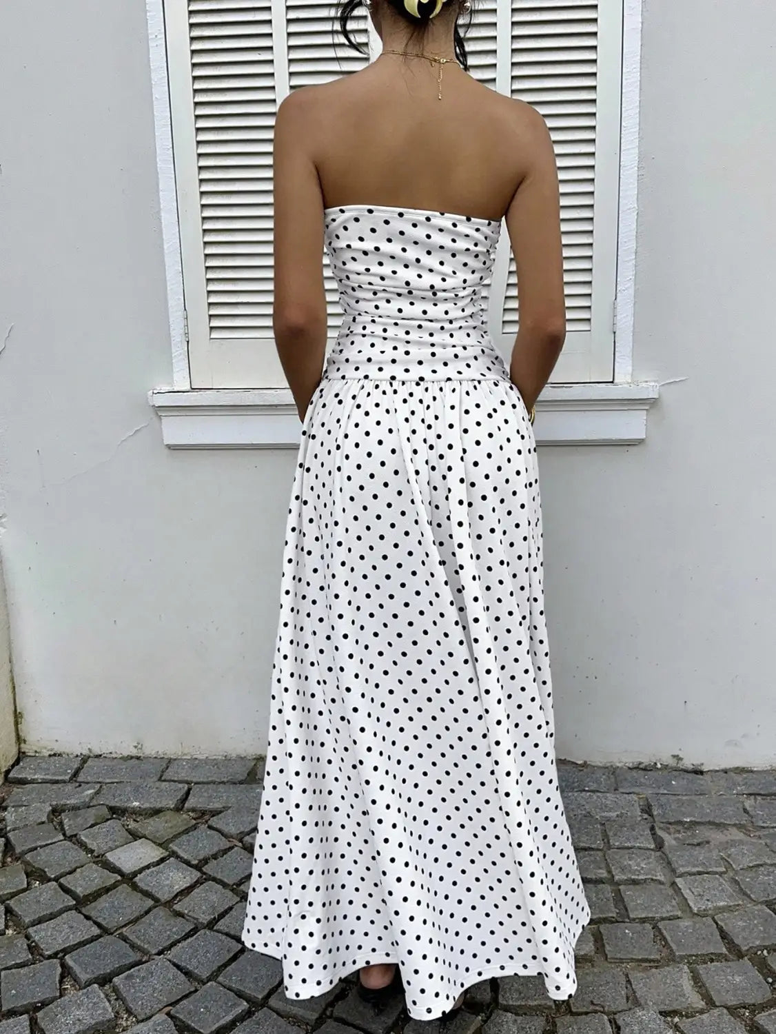 A strapless white maxi dress with black polka dots featuring a ruched bodice and flowing skirt, showcasing the polka dot off shoulder strapless maxi dress.