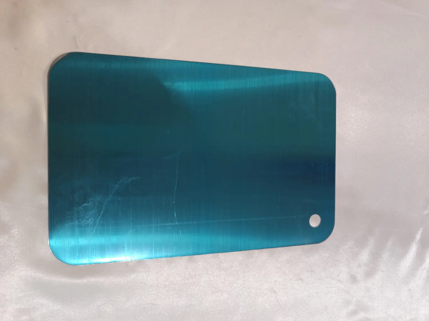 Planche à découper rectangulaire élégante en acier inoxydable couleur bleu canard, avec coins arrondis et petit trou pour poignée, conçue pour un usage anti-moisissure.